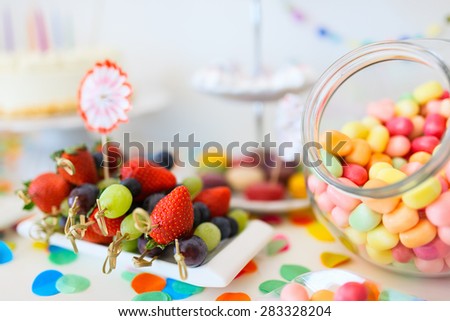 Cake, candies, marshmallows, cakepops, fruits and other sweets on dessert table at kids birthday party
