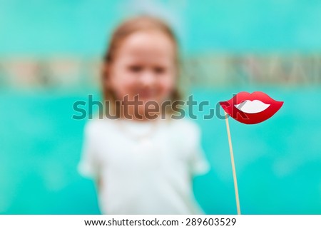 Adorable little girl holding lips party accessory