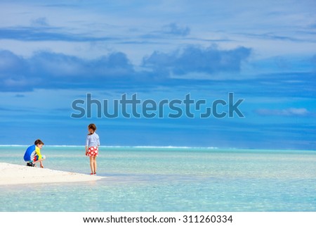 Little kids in rash guards for sun protection on tropical beach during summer vacation