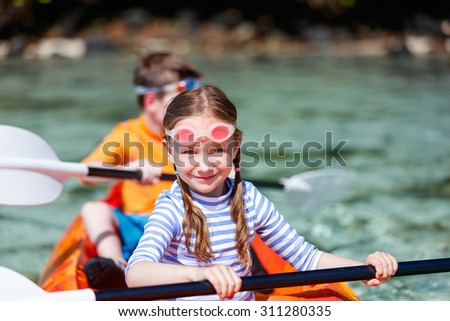 Kids enjoying paddling in colorful red kayak at tropical ocean water during summer vacation