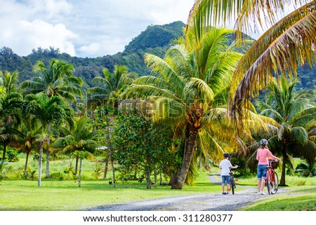 Back view family of mother and son biking at tropical settings having fun together