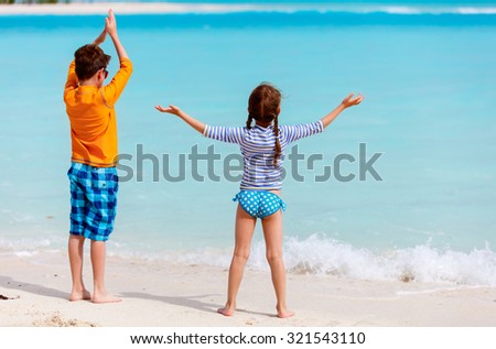 Little kids in rash guards for sun protection on tropical beach during summer vacation