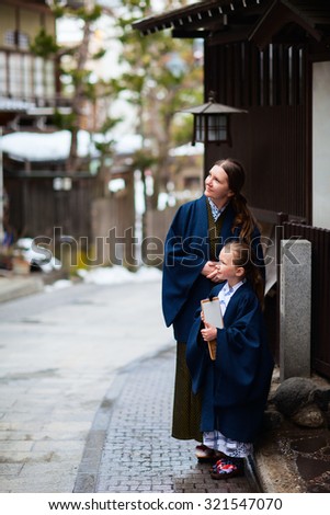Family of mother and daughter wearing yukata traditional Japanese kimono at street of onsen resort town in Japan going to public hot spring spa.