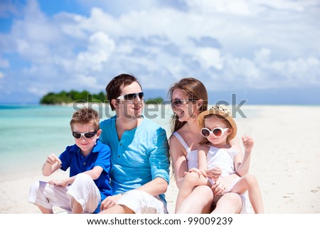 Young beautiful family with two kids sitting on tropical vacation
