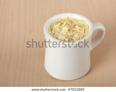 Cup of chicken noodle soup on a wooden table background