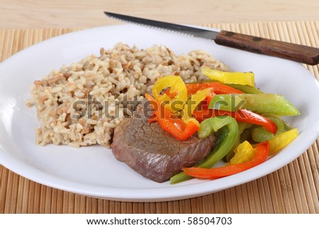 Beef sirloin steak covered with red and green peppers with rice