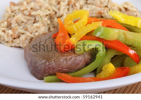 Sirloin steak meal covered with red and green bell peppers along with rice