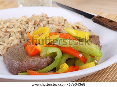 Steak dinner topped with peppers and rice