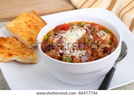 Bowl of chili with beans topped with melted cheese