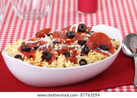 Bowl of pasta noodles with pepperoni and black olives