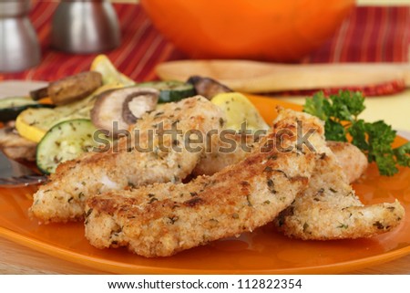 Fried breaded chicken tenderloins on an orange plate