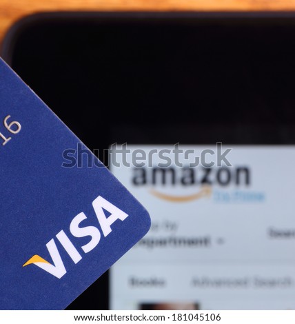 PETERSBURG, ILLINOIS-MARCH 8, 2014:  Closeup of a Visa credit card with a tablet showing Amazon\'s web site in background. Visa, Inc. is an American financial services corporation.