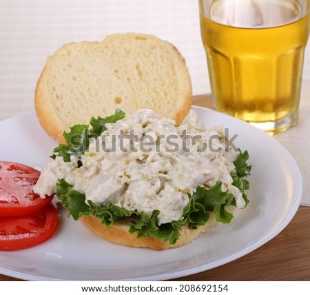 Chicken salad and lettuce on a bun with tomato slices on the side