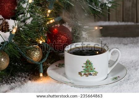 Christmas cup of coffee on snow with decorations in background