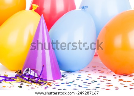 Birthday party hat and balloons with confetti and a noisemaker