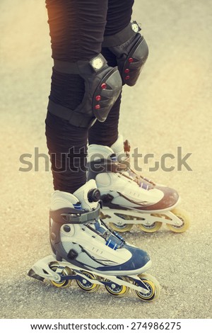 Close-up view of female legs in roller blades. Toned image.
