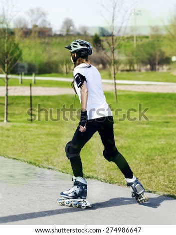 Roller skating girl in park rollerblading on in line skates and listening to music