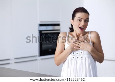 Portrait of beautiful surprised young woman thinking in the her kitchen