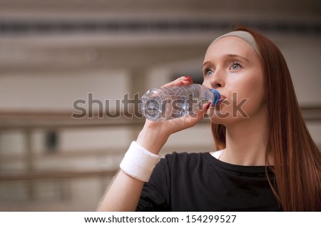 Woman drinking water at the gym after working out