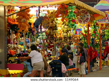 People enjoying the competition of amusement park games Prizes hang at an amusement park game