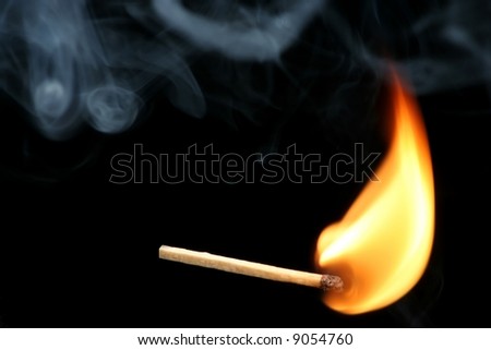 Burning match stick and smoke against a black background