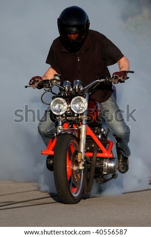 Motorbike rider on custom bike burning back tire and creating smoke