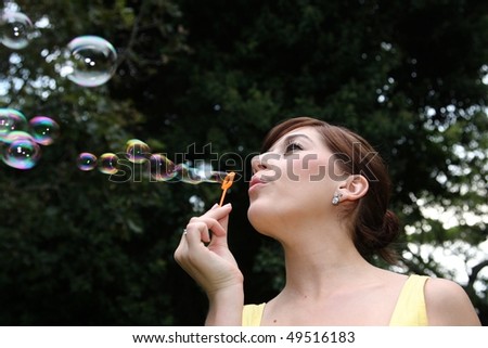 Beautiful woman blowing soap bubbles outdoors