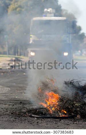 Burning rubber tyres in the streets in South Africa with police riot vehicle in the background