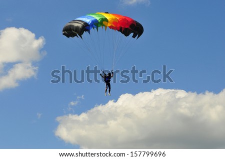 colorful parachute on blue sky with white clouds.