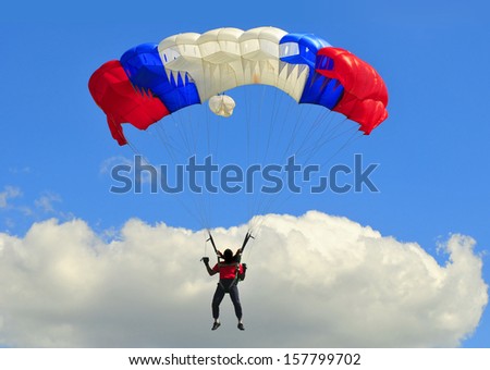 Blue white and red sail parachute on blue sky with white cloud