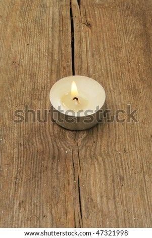Single tea light candle on old weathered wood