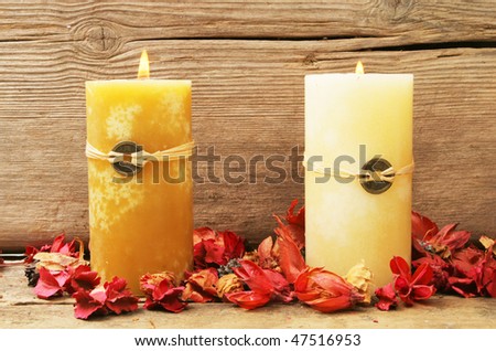 Two burning feng shui candles with dried flowers on a background of old wood