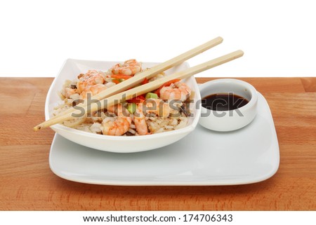 Asian meal with chopsticks and soy sauce on a wooden table against a white background
