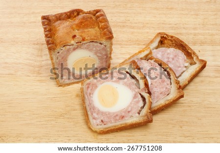 Pork and egg pie with cut slices on a wooden board