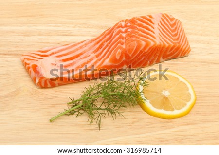 Raw sea trout fillet with fennel and lemon on a wooden board