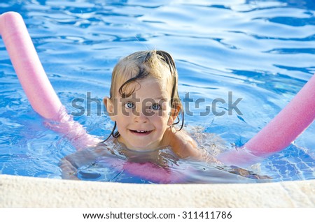 Funny little girl learning to swim with pool noodle