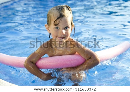 Funny little girl learning to swim with pool noodle