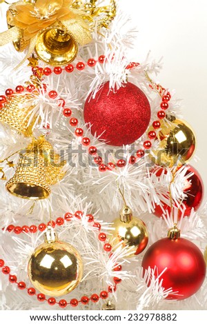 Red and golden decorations are on white Christmas tree.