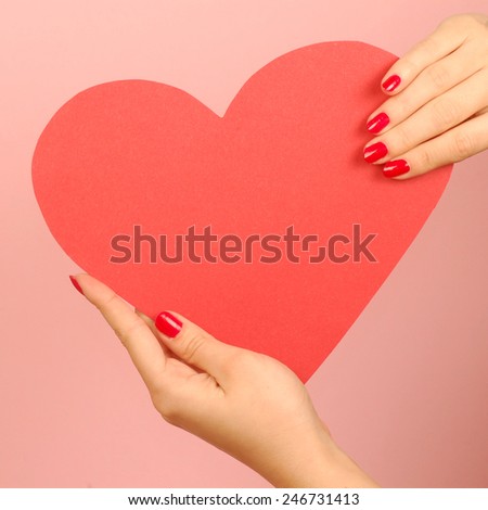Red heart from paper in hands on red background.