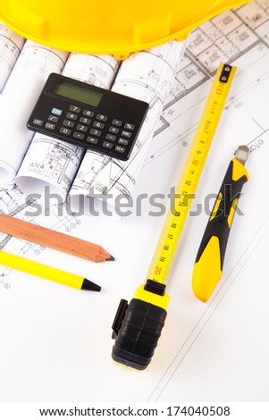 architectural accessories. yellow hardhat, measure, pencils, plans