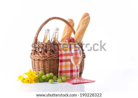Composition of picnic basket, flowers, baguettes,  grapes, bottles of water and glass of wine