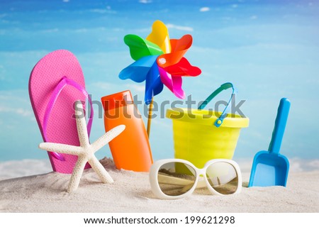 Collection of beach items - flip-flops, starfish, sunglasses, lotion, child\'s bucket, spade and other toys