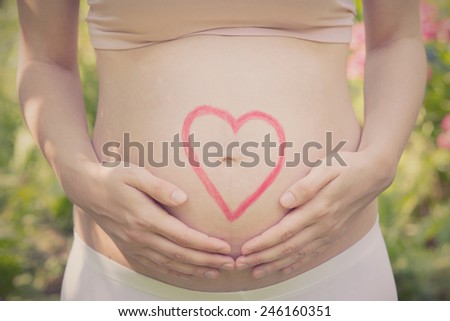 Conceptual image of pregnant belly with painted heart - vintage effect