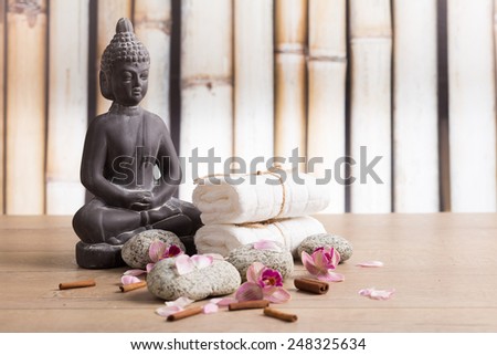 Grey Buddha statue with white towels and orchid flowers