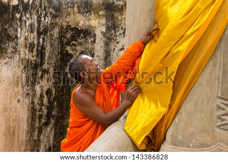 SUPHANBURI, THAILAND-JUNE 15: Monk care yellow robe of buddhist statue in old chapel at Wat Sri Rattana Mahathat and old temple built 600 years ago. on June 15, 2013 in Suphanburi, Thailand
