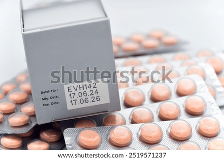 Manufacturing date and expiry date on some pharmaceutical packaging with strips of orange tablets.