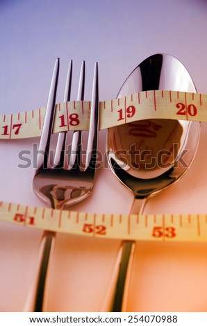 Tape Measure, Fork and Spoon in Waistline and Weight Control Concept by Diet Control.