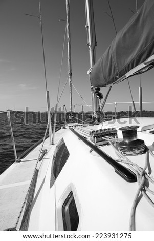 Ropes and winch on a sailing vessel. View on deck of sailing yacht. Monochrome picture from perspective of sitting on deck of yacht