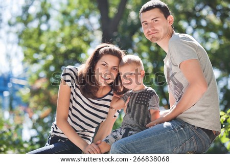 Young parents with a little boy sitting on the nature of summer day