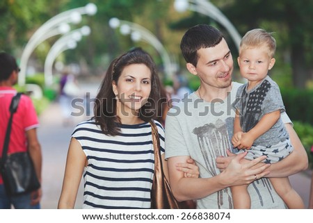 Parents and young son walking in the city park summer day
